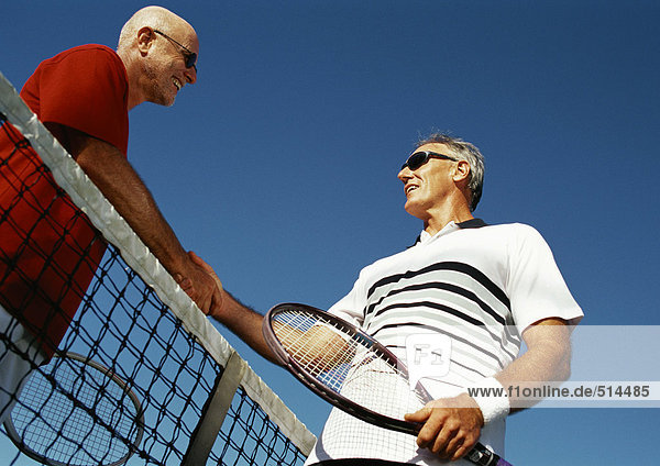 Zwei reife Männer beim Händeschütteln über dem Tennisnetz  Blick in den niedrigen Winkel