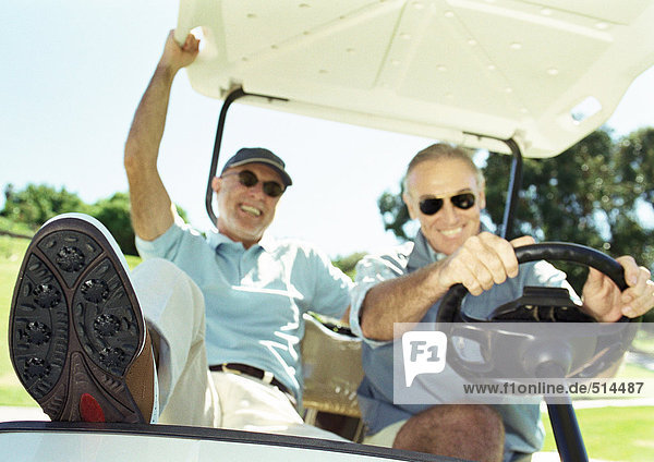 Zwei reife Männer im Golfwagen  lächelnd  Nahaufnahme