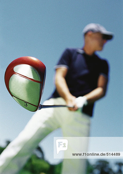 Mature man holding golf club  low angle view  blurred