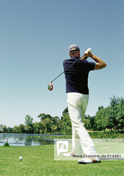 Mature man playing golf  rear view