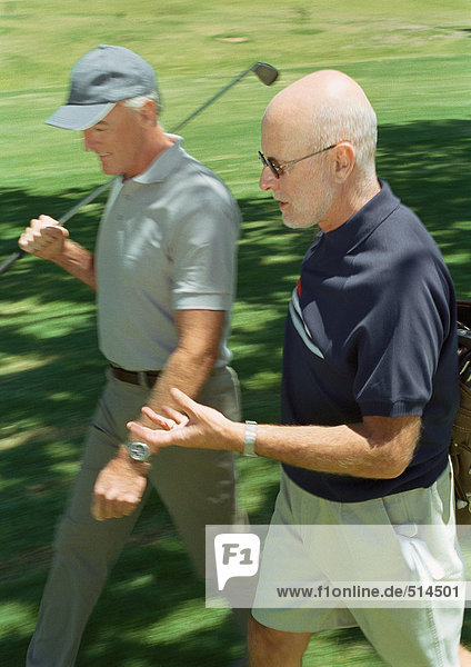 Two mature golfers walking on green