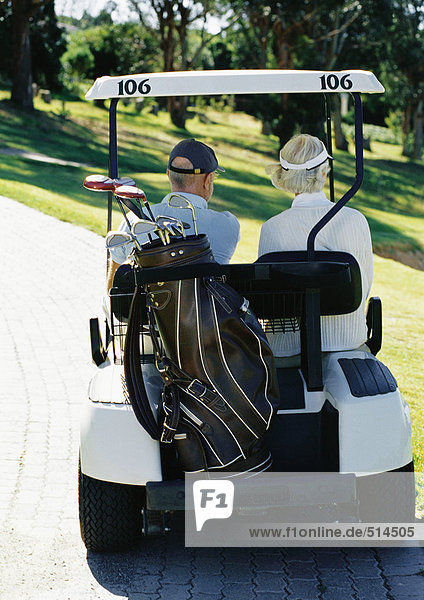 Mature man and woman in golf cart  rear view