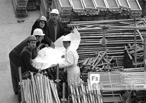 Fünf Personen untersuchen Baupläne auf der Baustelle  Porträt  s/w