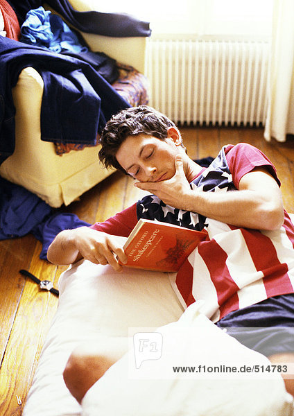 Mann liest Buch auf dem Bett