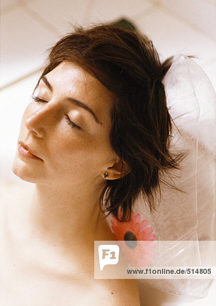 Woman taking bath  close-up of head resting on plastic pillow