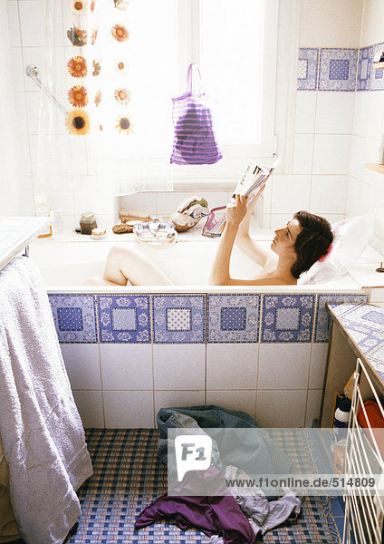 Young woman reading in bathtub