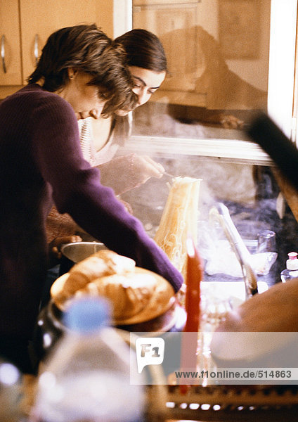 Women preparing pasta in kitchen