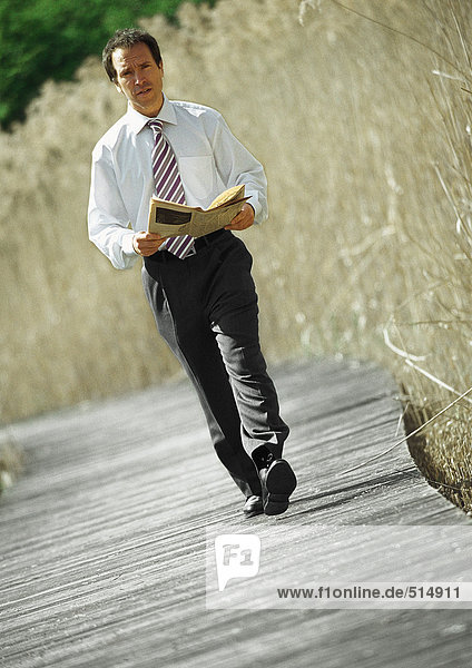 Geschäftsmann zu Fuß mit Zeitung in den Händen  im Freien  Porträt