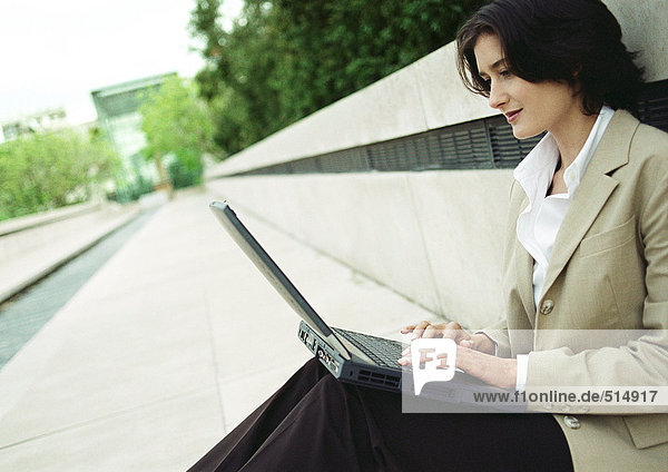 Geschäftsfrau sitzend mit Laptop im Freien