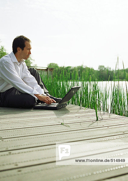 Mann im Freien sitzend mit Laptop-Computer