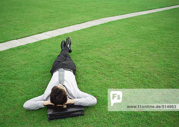 Mann auf Gras liegend  Kopf auf Aktentasche