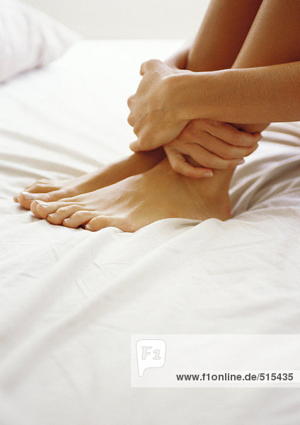 Woman holding ankles  close up.