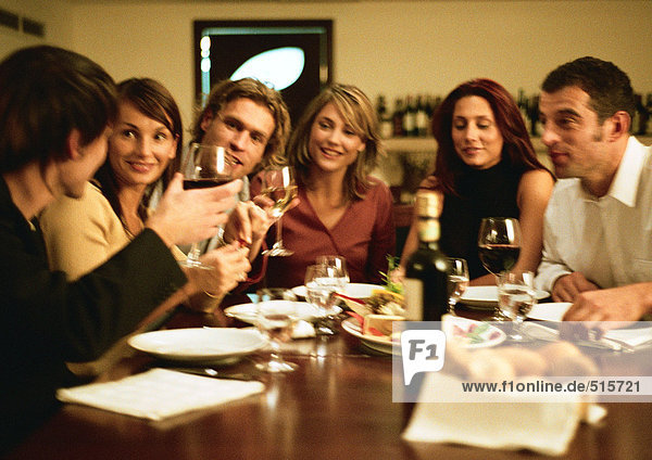 Group of young people sitting at table  having dinner together