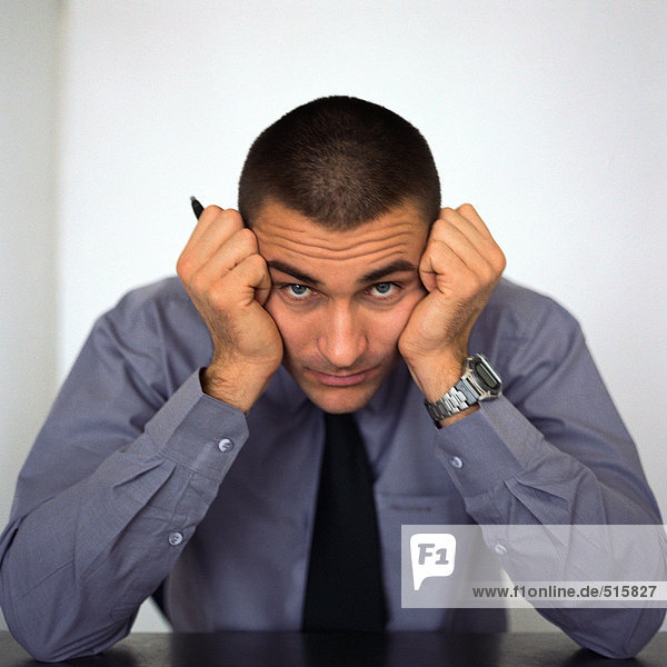 Businessman sitting with head between fists  portrait