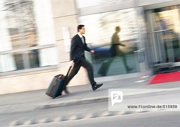 Businessman walking on sidewalk with luggage  blurred