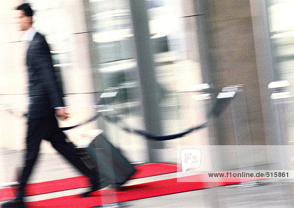 Businessman walking with luggage  side view  blurred