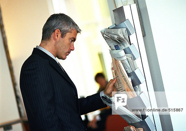Businessman looking at newspapers on wall rack