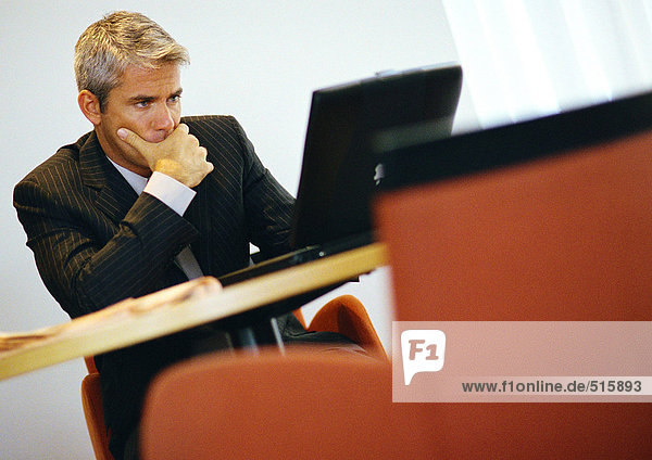 Businessman  hand to chin  working on computer
