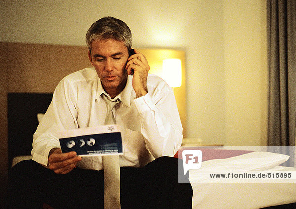 Businessman talking on cell phone  looking at ticket