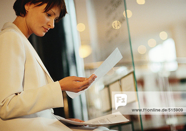 Businesswoman looking at documents near window