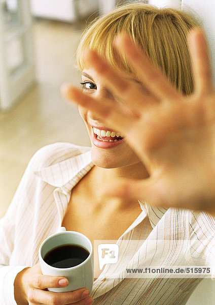 Teen girl with coffee holding hand in front of face  laughing