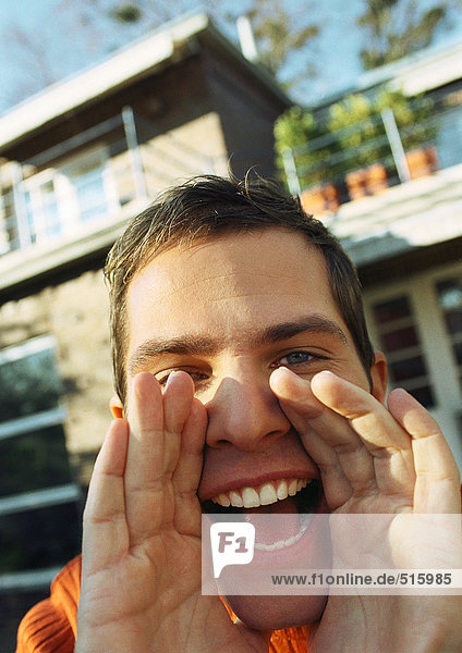 Man holding hands up to mouth  shouting  house in background