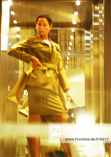 Woman standing with hand on hip  holding shopping bags  blurred.