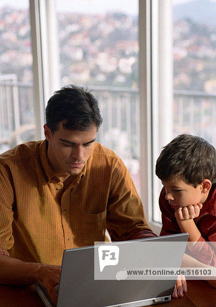 Vater und Sohn arbeiten am Computer.