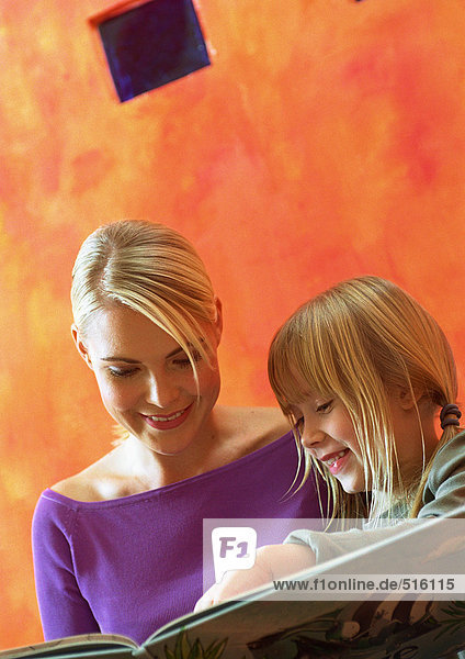 Junge Frau und kleines Mädchen mit Blick auf Buch  Kopf und Schultern