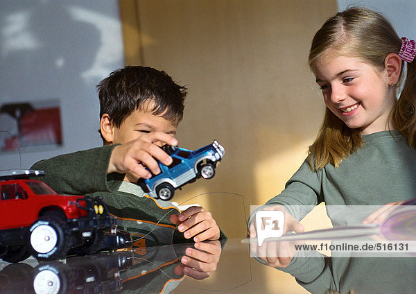 Junge und Mädchen spielen zusammen am Tisch mit Spielzeugautos.