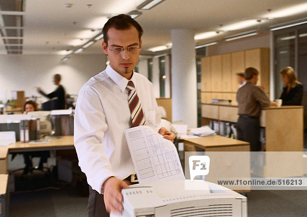 Businessman standing at printer in office