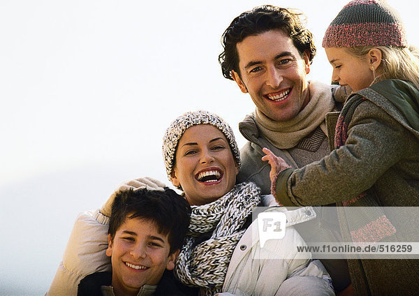 Erwachsener Mann und Frau mit zwei Kindern  lächelnd  warm gekleidet  Außenseite  Portrait