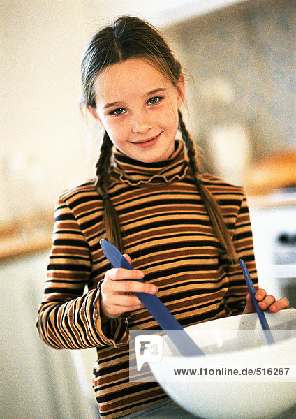Junges Mädchen tailliert  hinter weißer Rührschüssel stehend  Utensilien in Schüssel haltend  lächelnd  in Kücheneinstellung  kippbar