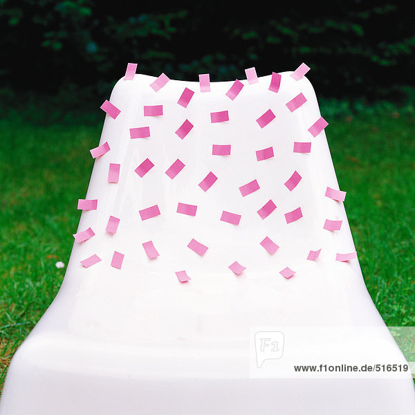 Rosa Klebezettel auf weißem Kunststoffstuhl aufgeklebt