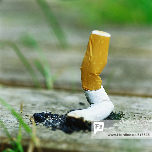 Ausgelöschter Zigarettenstummel auf Holzbohle
