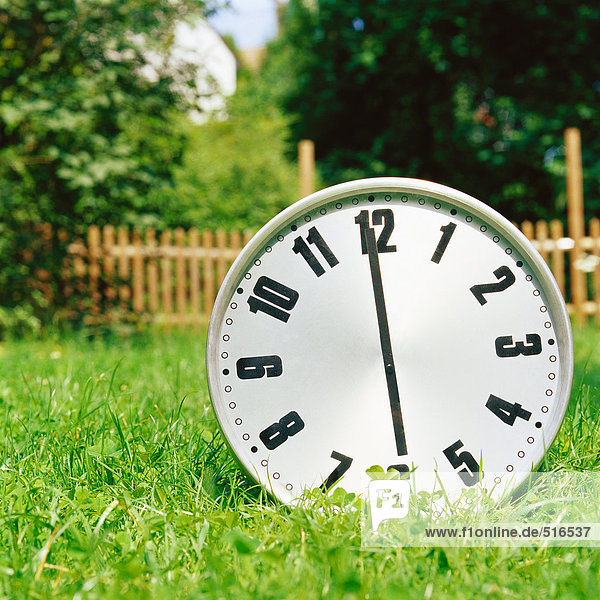 Uhr auf dem Rasen mit sechs Uhr Anzeige