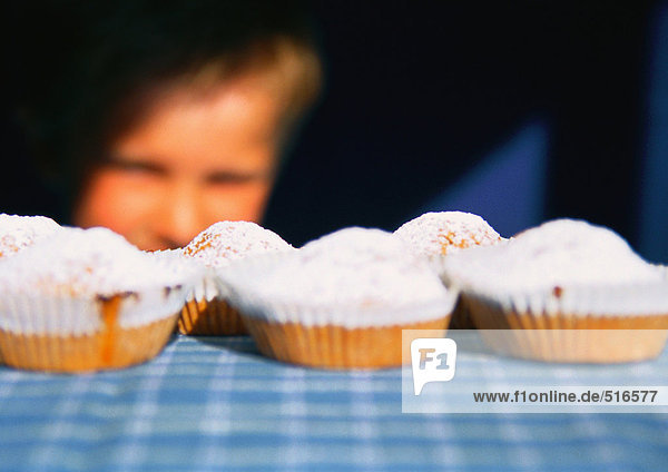 Kind schaut auf Muffins auf dem Tisch aufgereiht  selektive Fokussierung