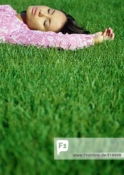 Frau auf Gras liegend mit geschlossenen Augen  Blick auf die Oberfläche