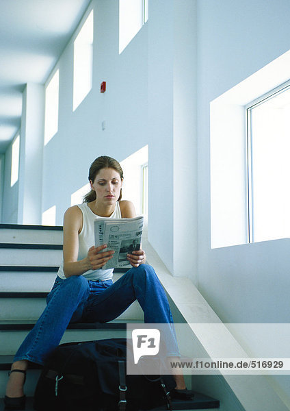 Frau auf der Treppe sitzend  Zeitung lesend  volle Länge