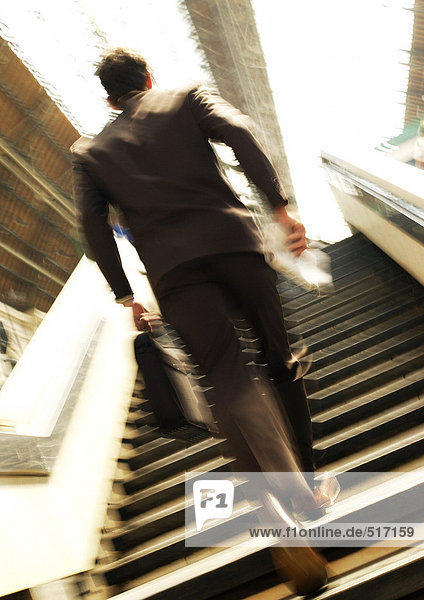 Geschäftsmann eilt im Bahnhof die Treppe hinauf  Rückansicht  verschwommene Bewegung
