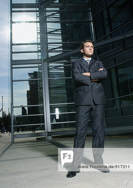 Businessman folding arms  building in background