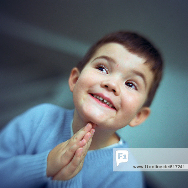 Boy smiling  looking to the side with hands together  portrait