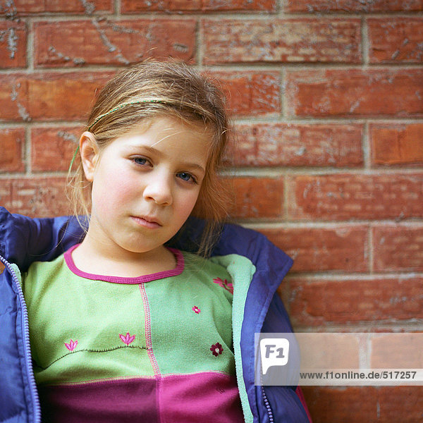 Girl leaning against brick wall  portrait