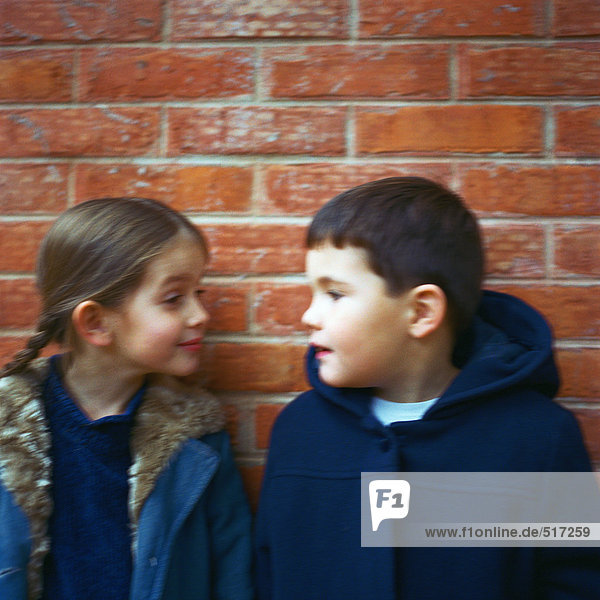 Boy and girl standing in front of brick wall  staring eachother down  blurred