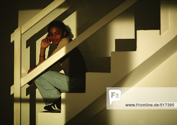 Junges Mädchen auf der Treppe sitzend  telefonierend  lächelnd