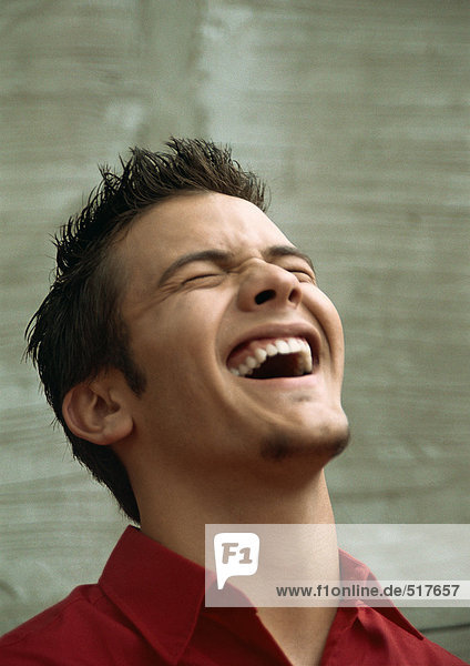 Teenage boy laughing  head back  eyes closed  portrait