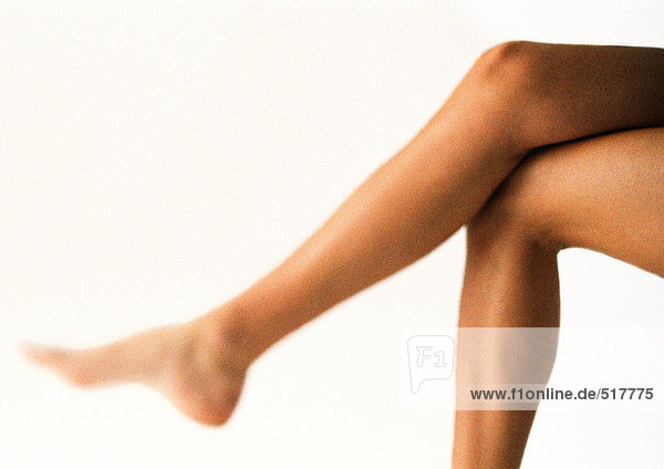 Die nackten Beine der Frau  gekreuzt am Knie