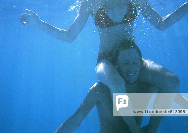 Mann mit Frau auf den Schultern  Unterwasseransicht