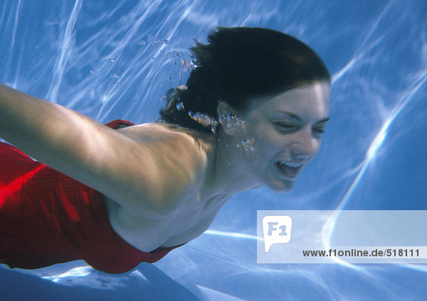 Frau schwimmt unter Wasser am Boden des Pools