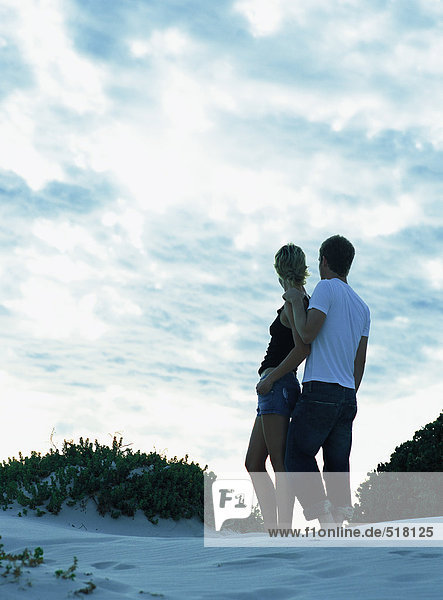 Couple standing together on sand dune  rear view